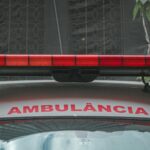 A close-up view of a city ambulance with a red siren light and Portuguese text 'AMBULÂNCIA'