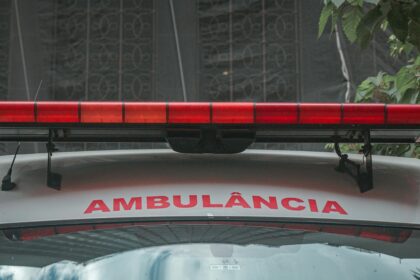 A close-up view of a city ambulance with a red siren light and Portuguese text 'AMBULÂNCIA'