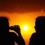 Two women silhouetted against a golden sunset, capturing the essence of evening tranquility.