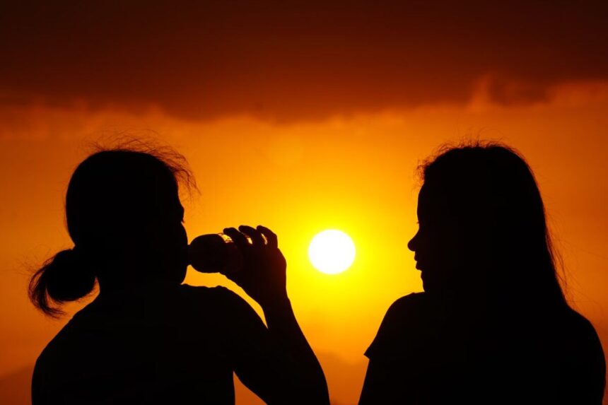 Two women silhouetted against a golden sunset, capturing the essence of evening tranquility.