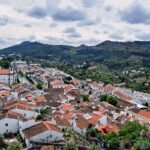 Aerial view of Marvão's charming white houses and red roofs against a mountainous backdrop in Portugal.