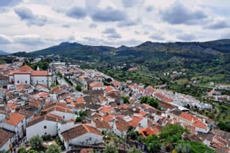Aerial view of Marvão's charming white houses and red roofs against a mountainous backdrop in Portugal.