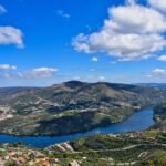 aerial view of green mountains and lake under blue sky during daytime